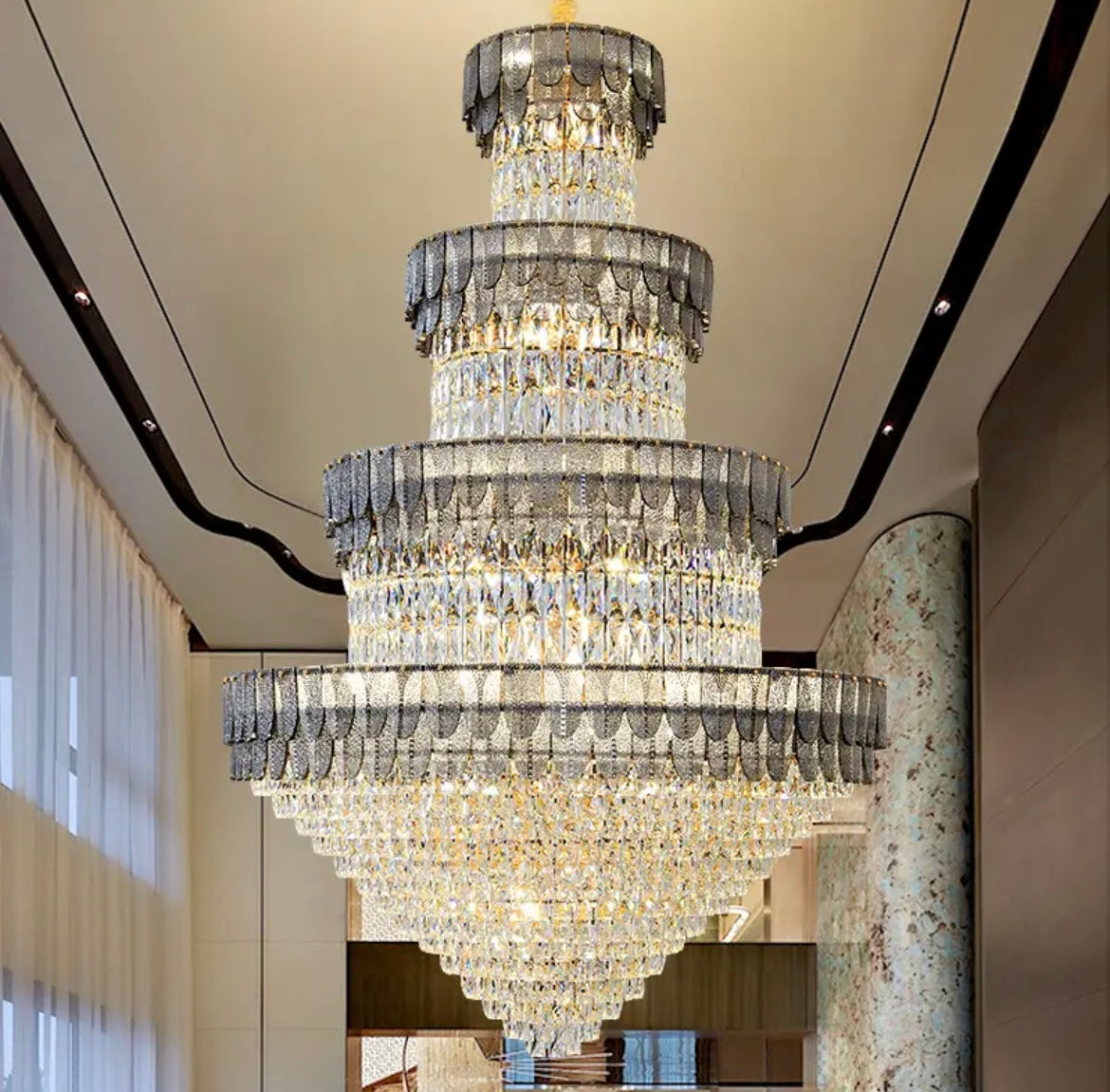 The chandelier hangs in the centre of a grand staircase, with its warm glow illuminating the steps below. 